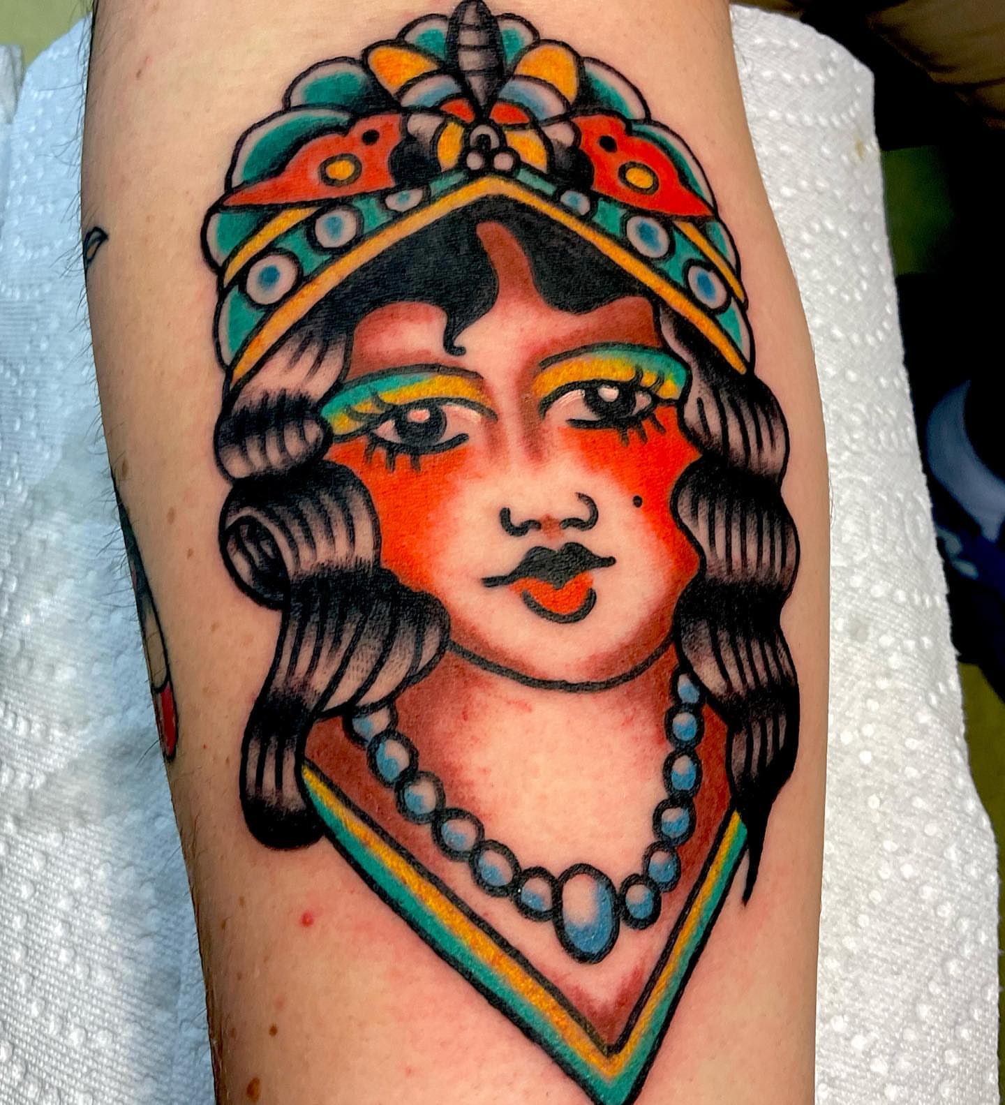 Woman with headdress American traditional tattoo on the forearm by Dorian Grey Baker