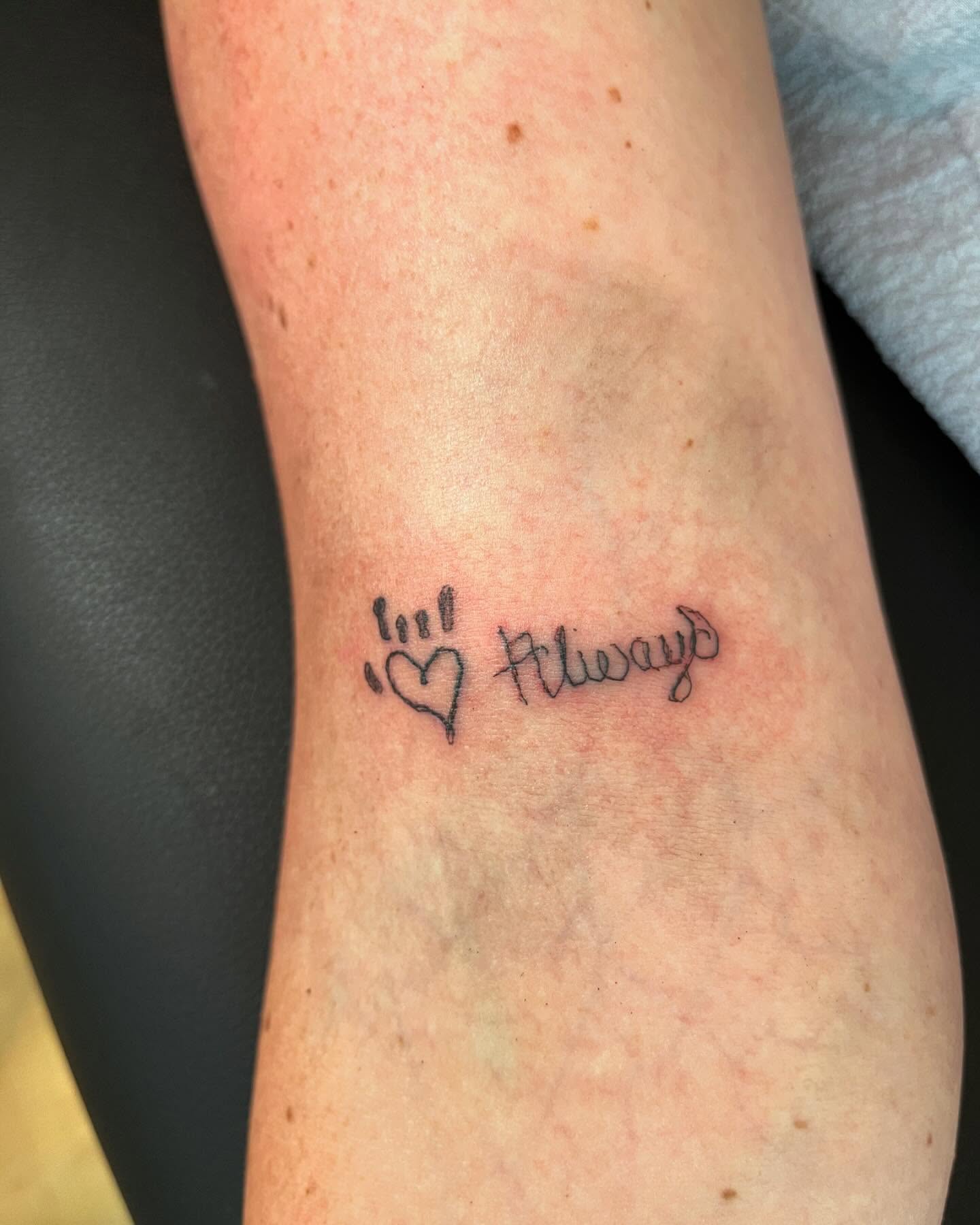 Paw print with heart and 'Always' lettering script tattoo on the forearm by Val Maughan