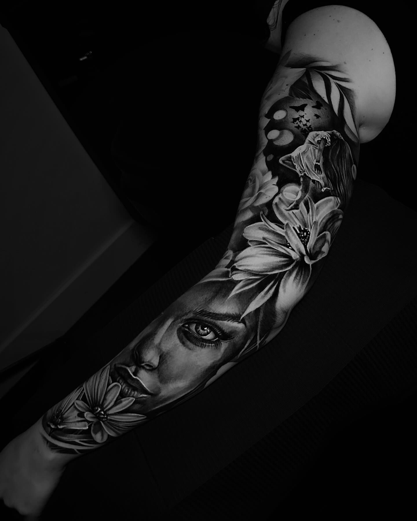Woman's face with floral elements realism tattoo on the forearm by Nick Stratt