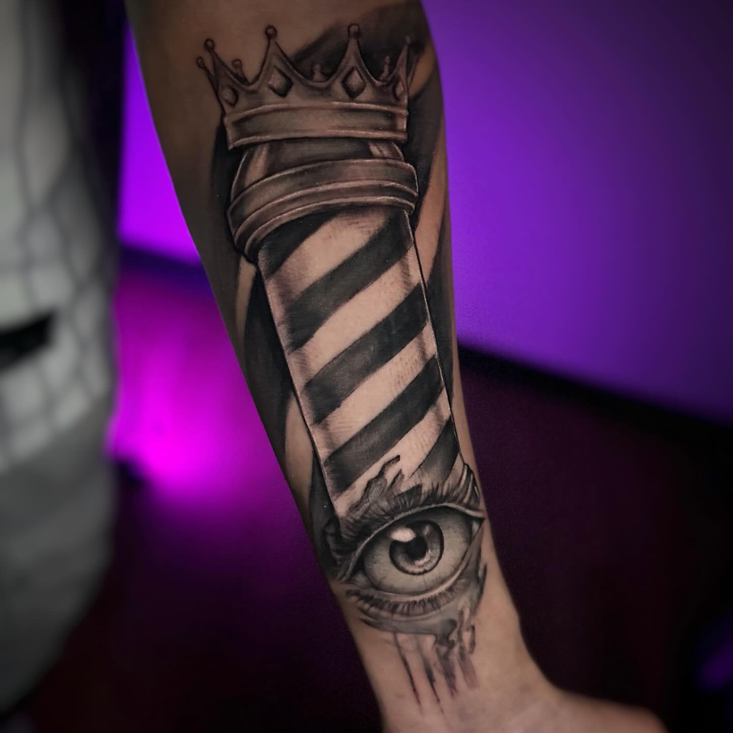 Barber pole with crown and eye realism tattoo on the forearm by Juan Russo