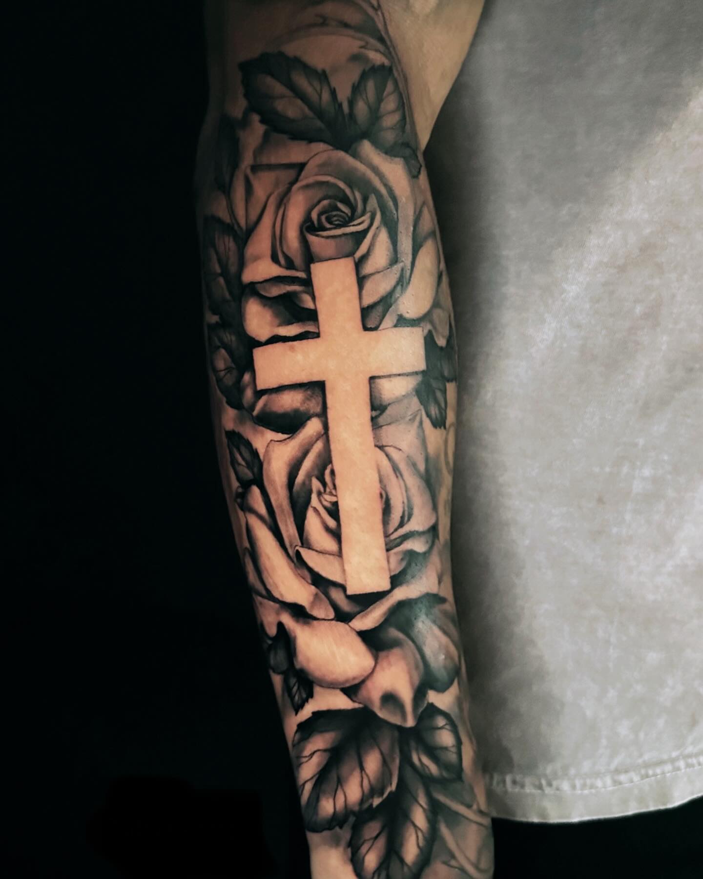 Cross and roses realism tattoo on the forearm by ⠀Joey Rosado