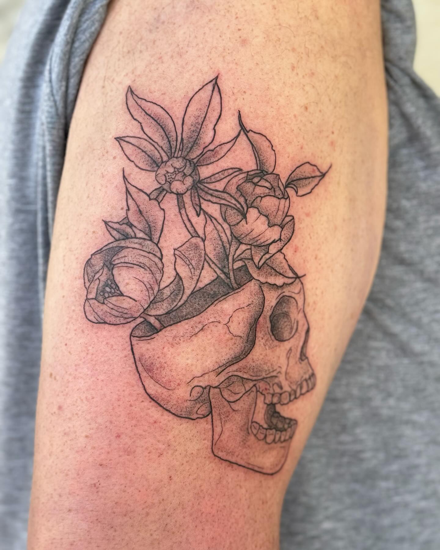 Skull and flowers dotwork tattoo on the forearm by Marissa Losier