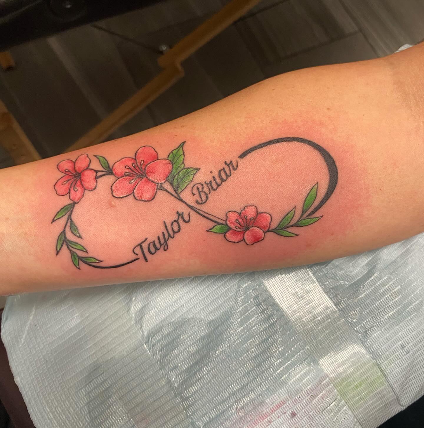 Flower and name fine line tattoo on the forearm by Missy (Miz)