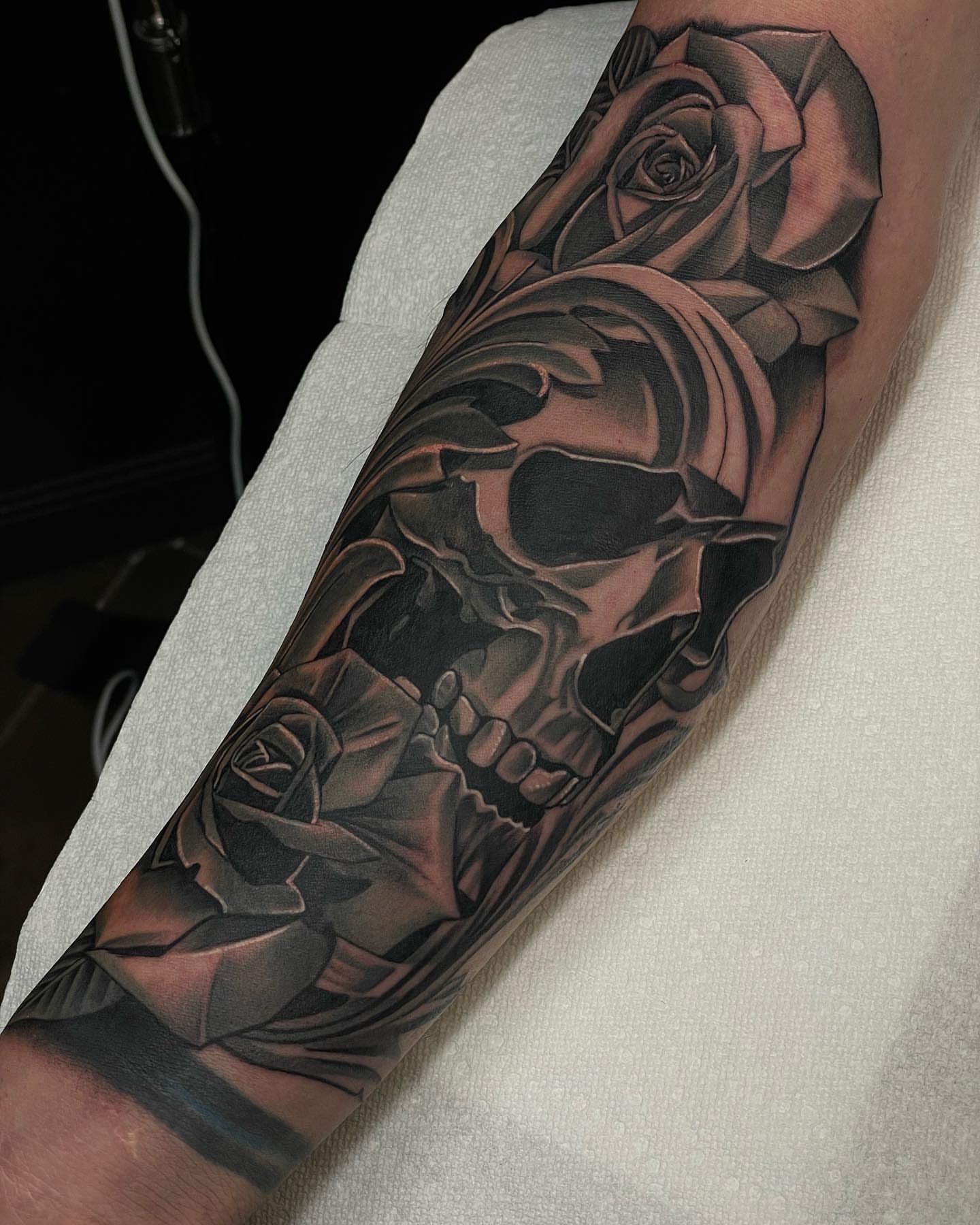 Skull and roses realism tattoo on the forearm by Jesse (Dreadzilla)