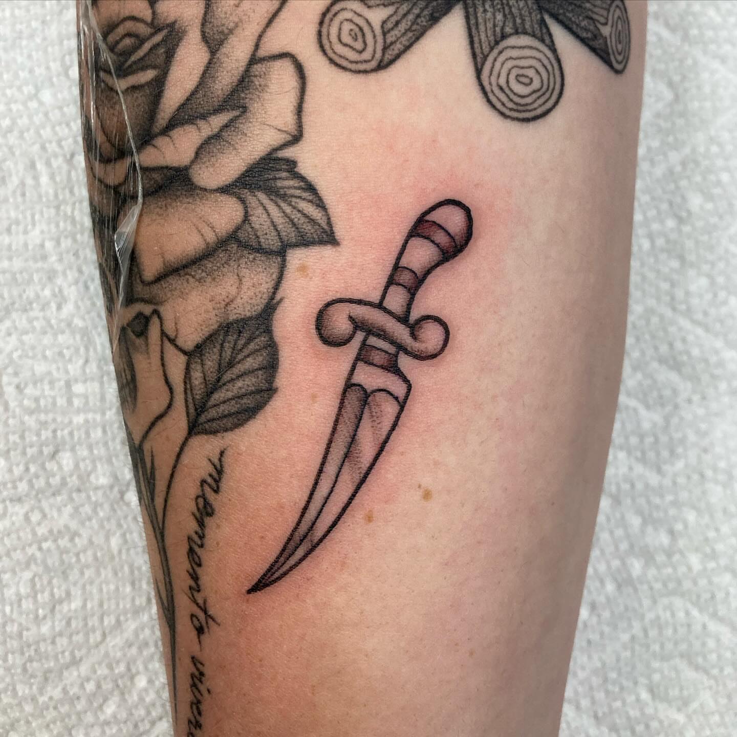 Knife and roses black and grey tattoo on the forearm by Hali Larkin