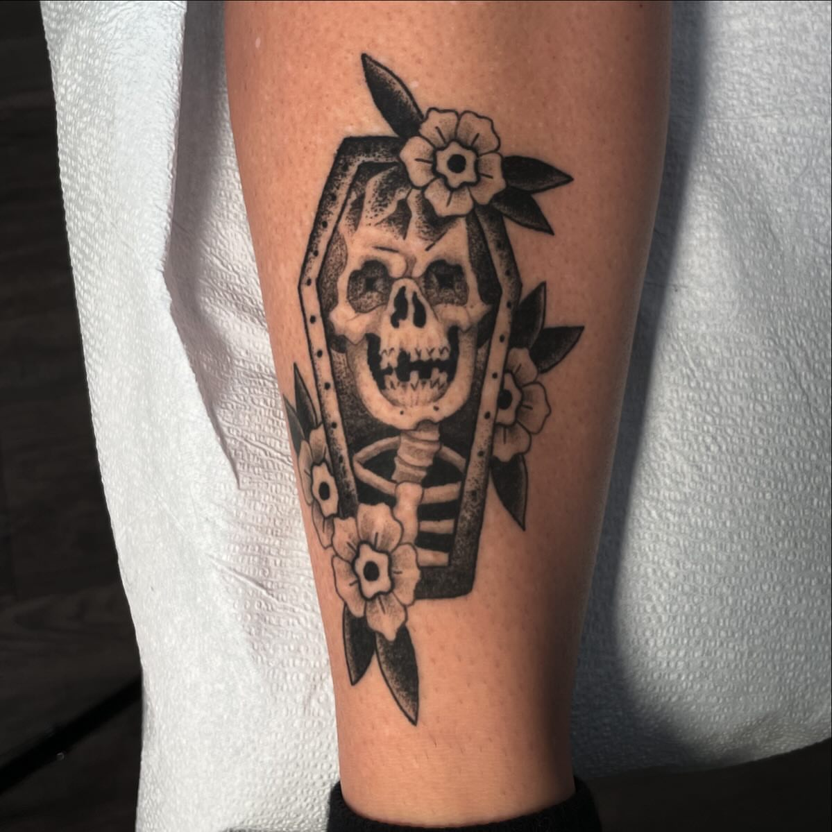 Coffin with skull American traditional tattoo on the calf by Caleb Baker