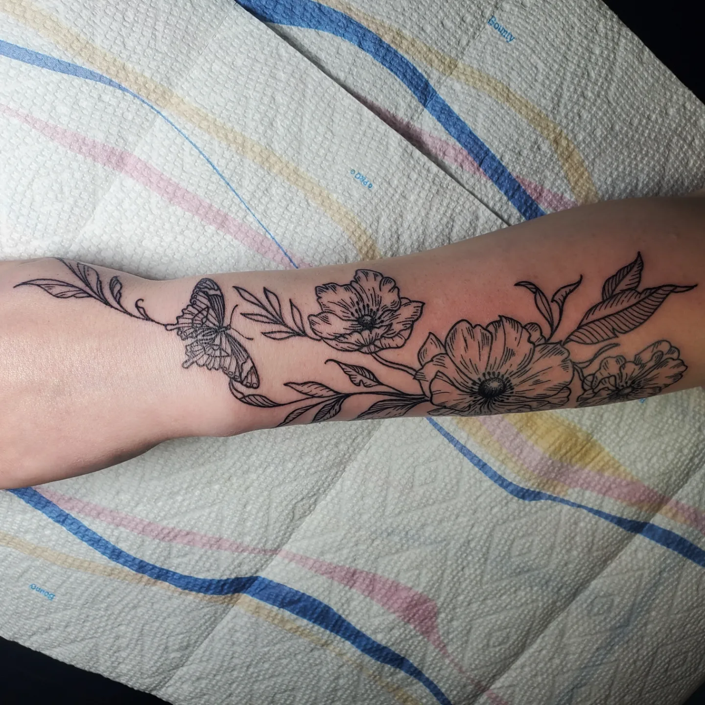 Flowers and butterfly black and grey tattoo on the forearm by Shailey Pasquale