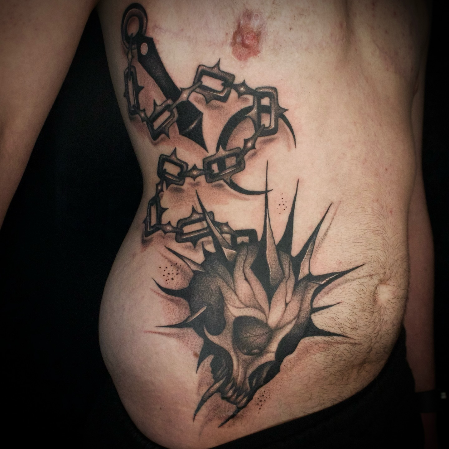 Skull and chains dark realism tattoo on the ribs by Galen