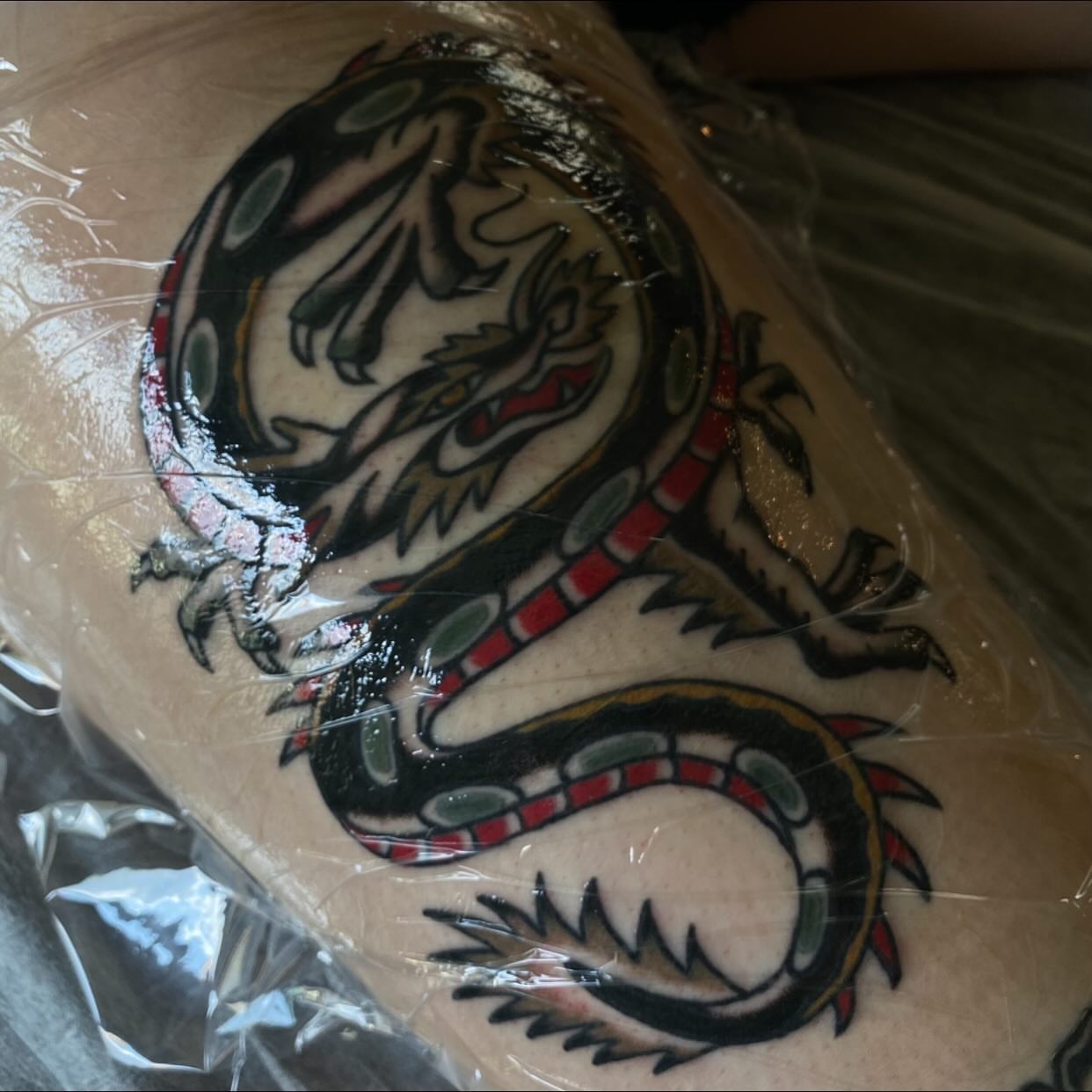 Dragon American traditional tattoo on the upper arm by Erin Chambers