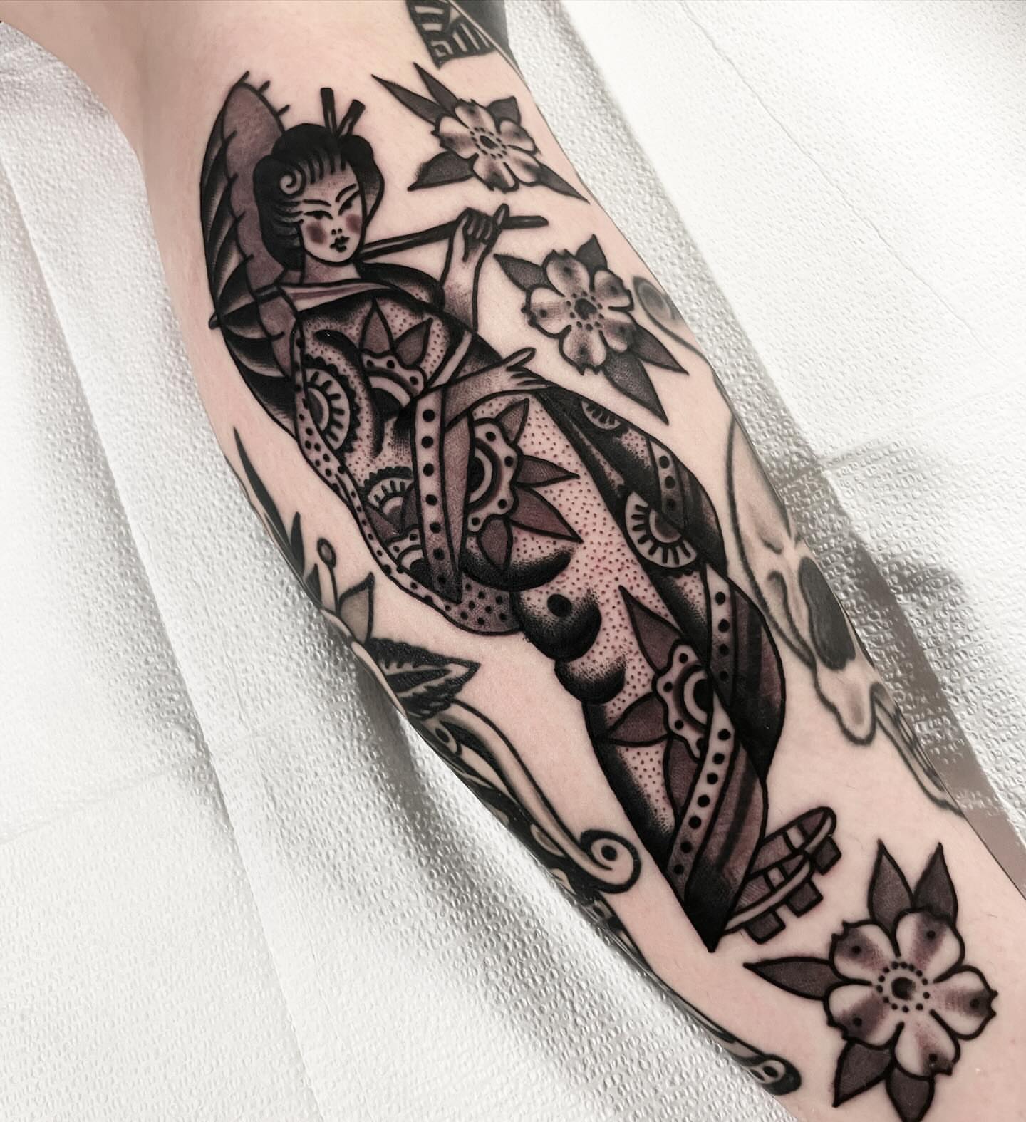 Geisha with flowers American traditional tattoo on the forearm by Mike Hudgins