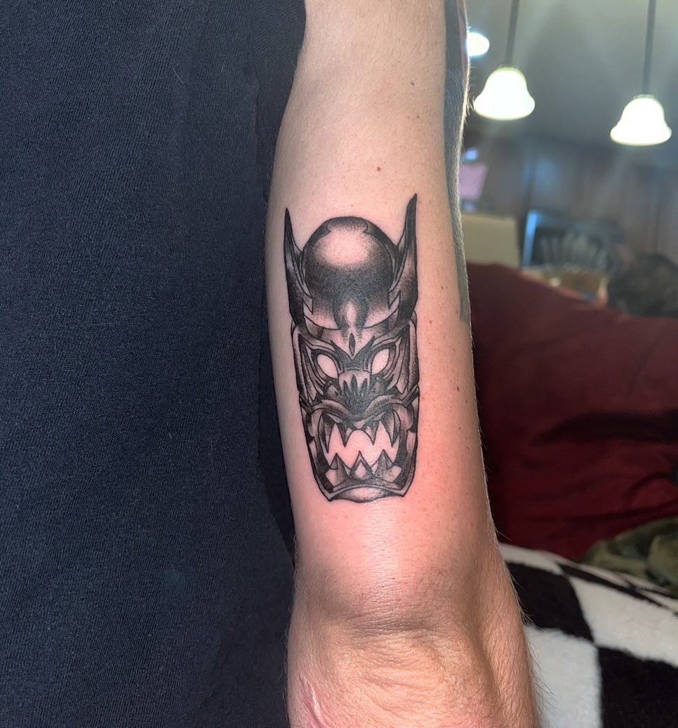 Demon mask black and grey tattoo on the forearm by ren