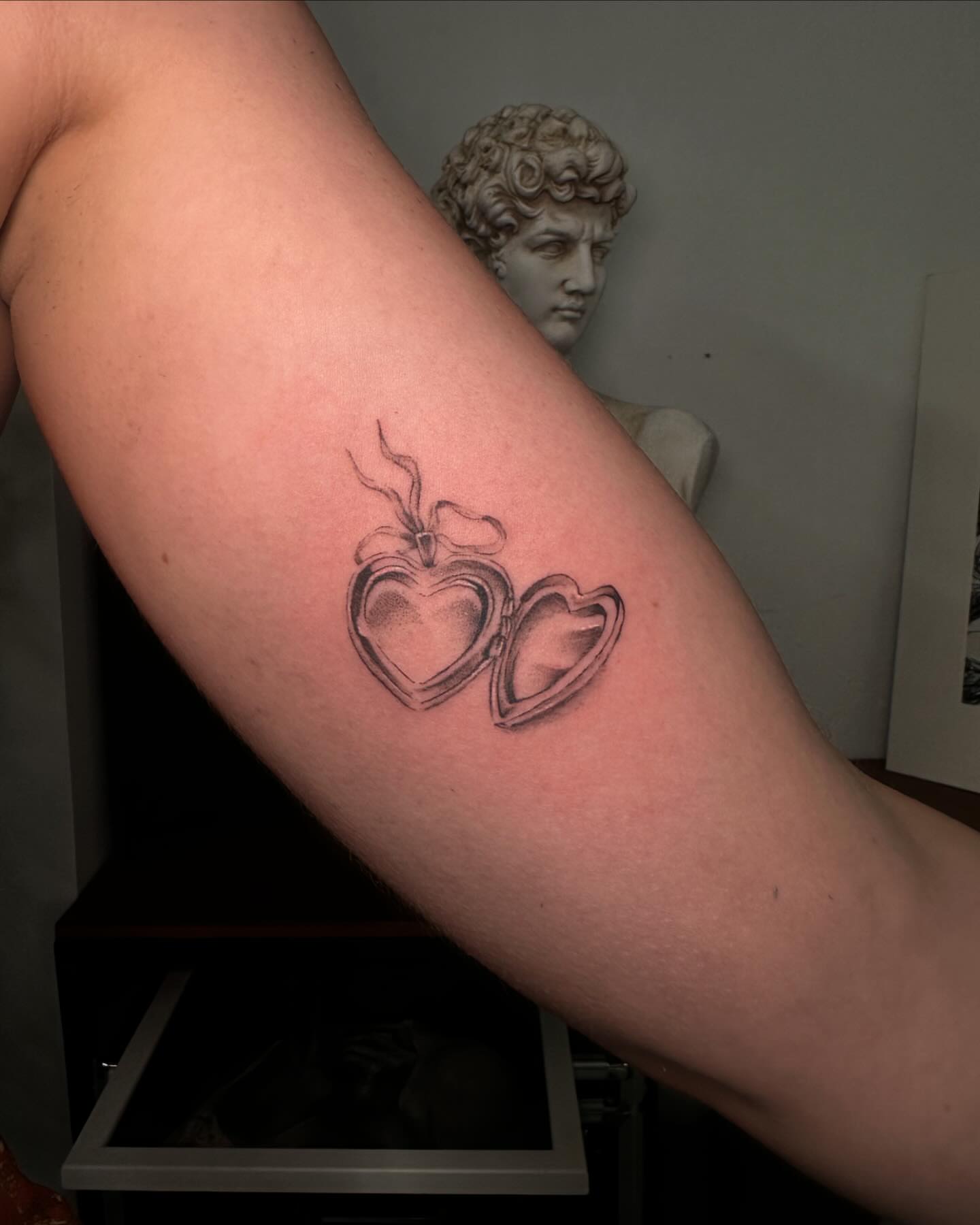 Heart locket black and grey tattoo on the forearm by chloe🗡️🖤🦇🩸