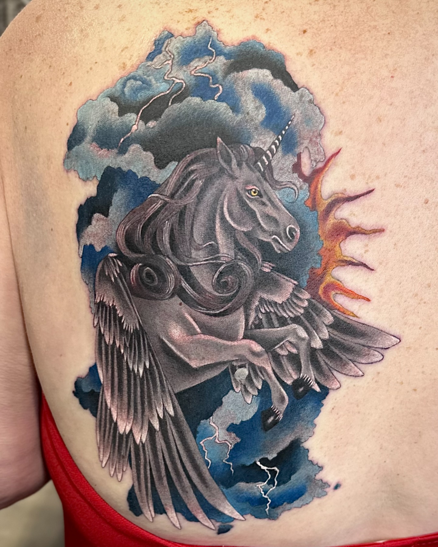 Winged unicorn dark realism tattoo on the shoulder by Savannah Compton