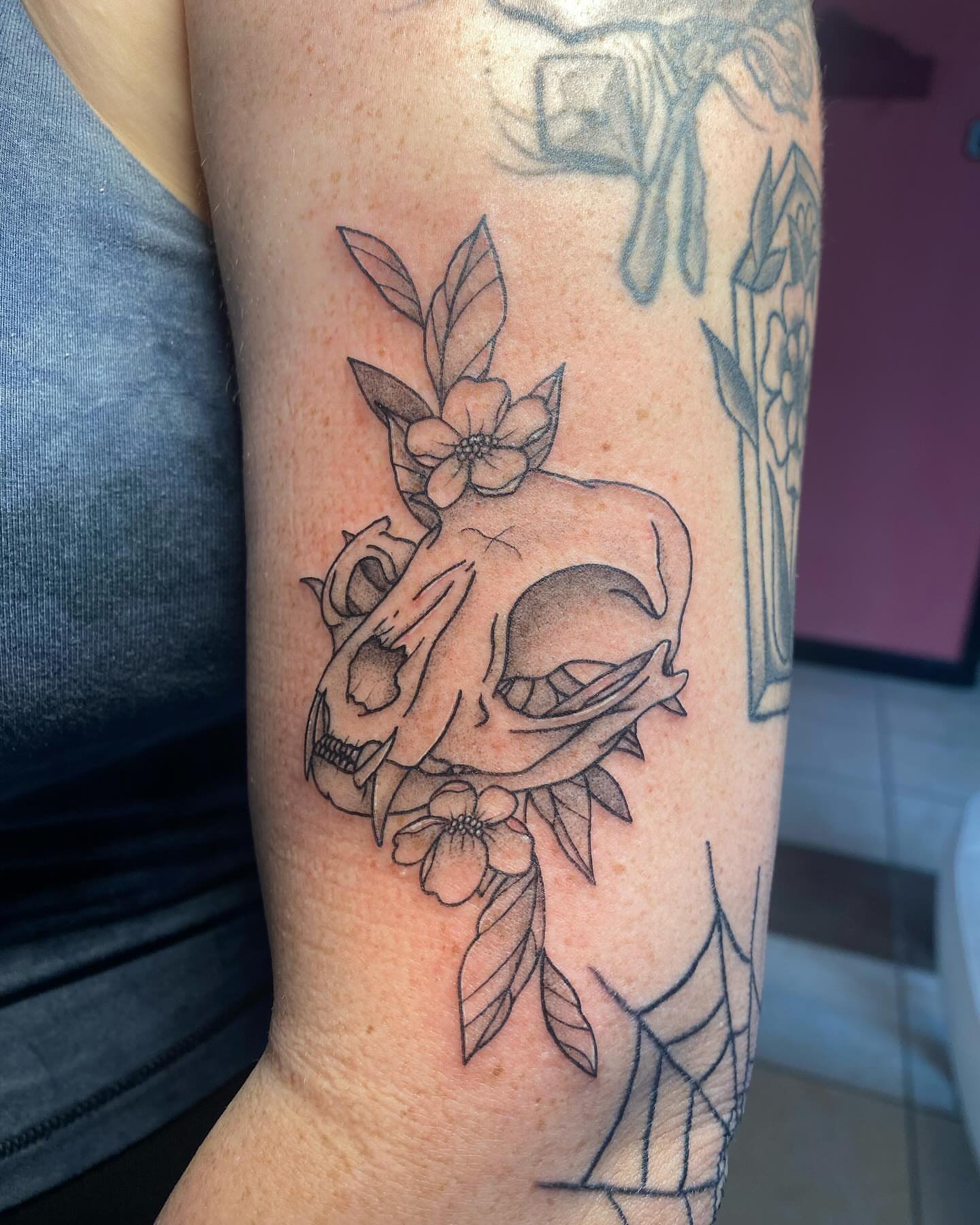 Skull with flowers black and grey tattoo on the forearm by Drew