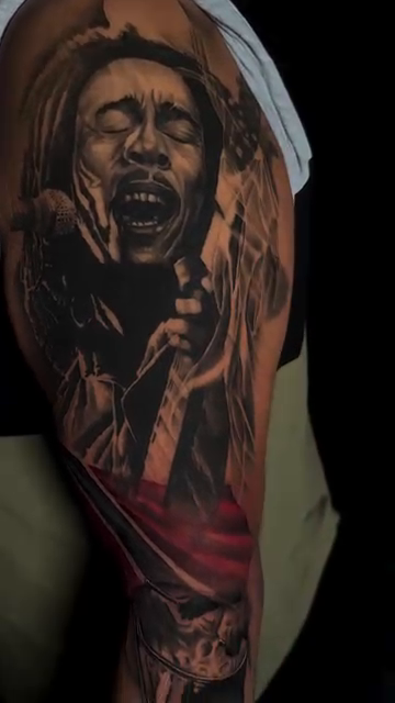 Bob Marley portrait with tropical scene realism tattoo by Brayan Molina