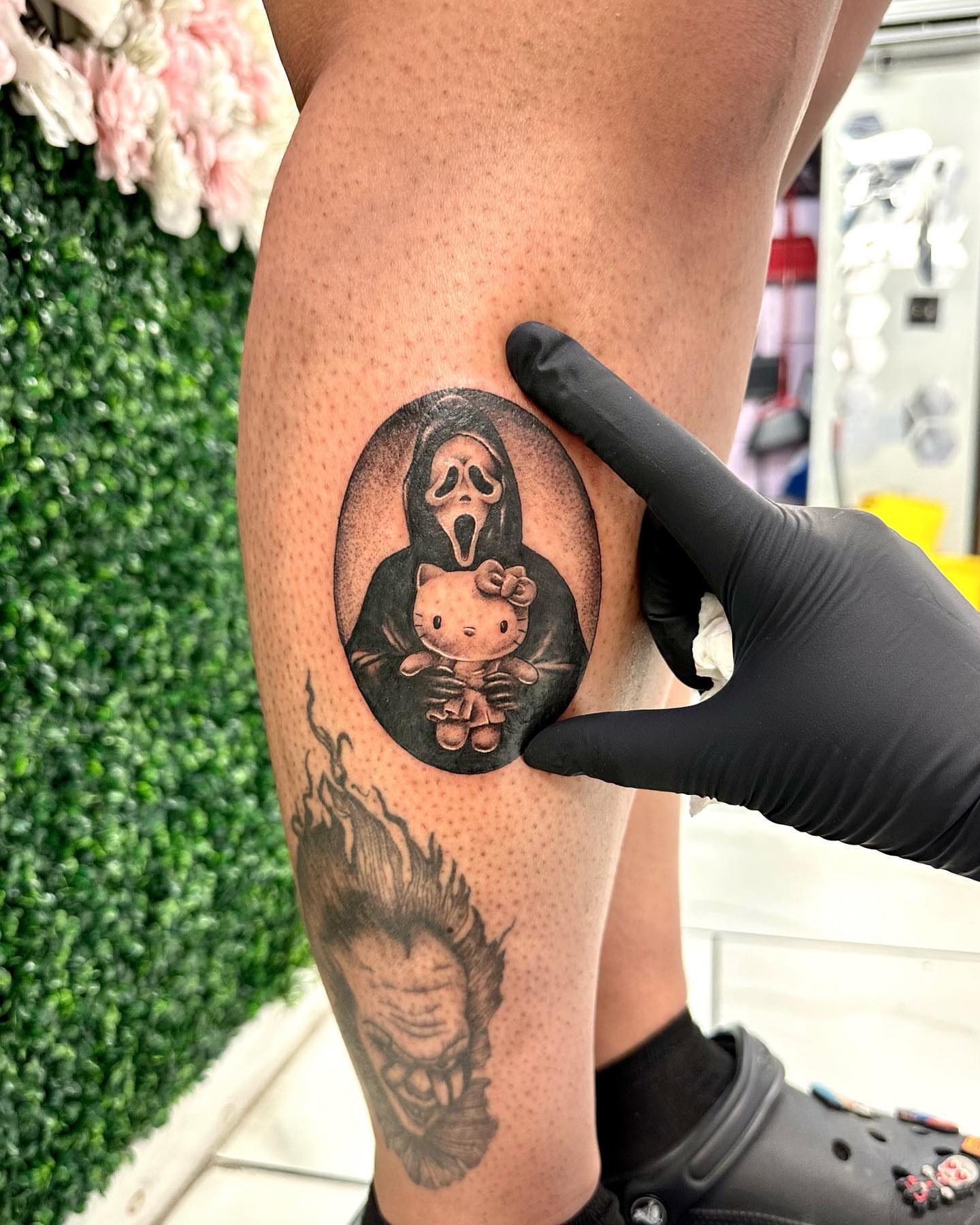 Hello kitty and ghostface black and grey tattoo on the thigh by Erika Nambo