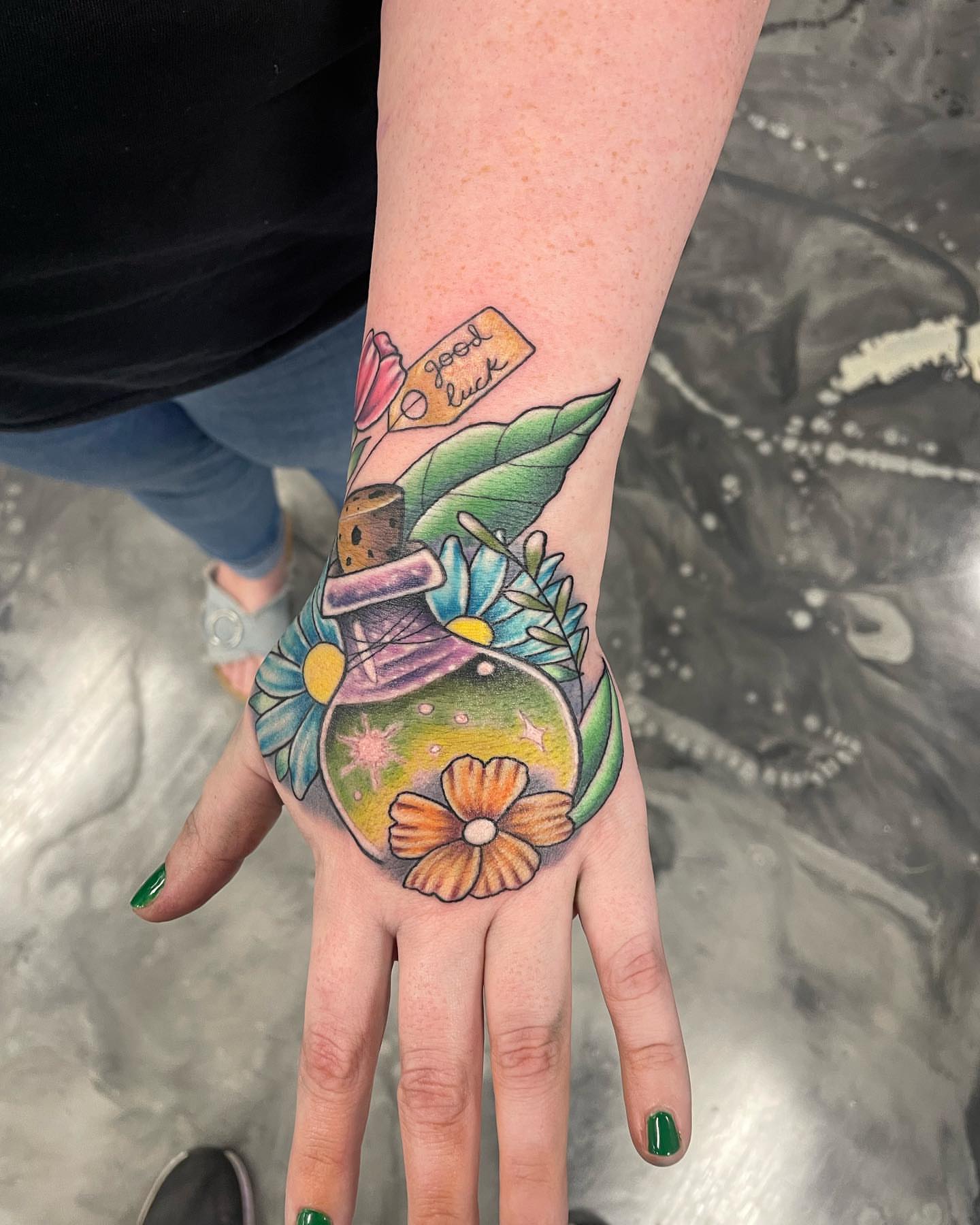 Bottle with flowers American traditional tattoo on the hand by Brandon Anderson