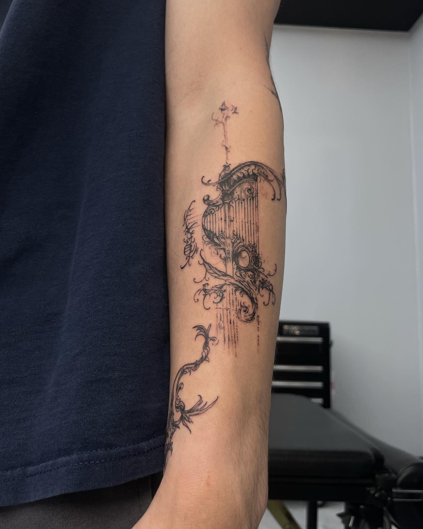 Harp black and grey tattoo on the forearm by Austin Jones