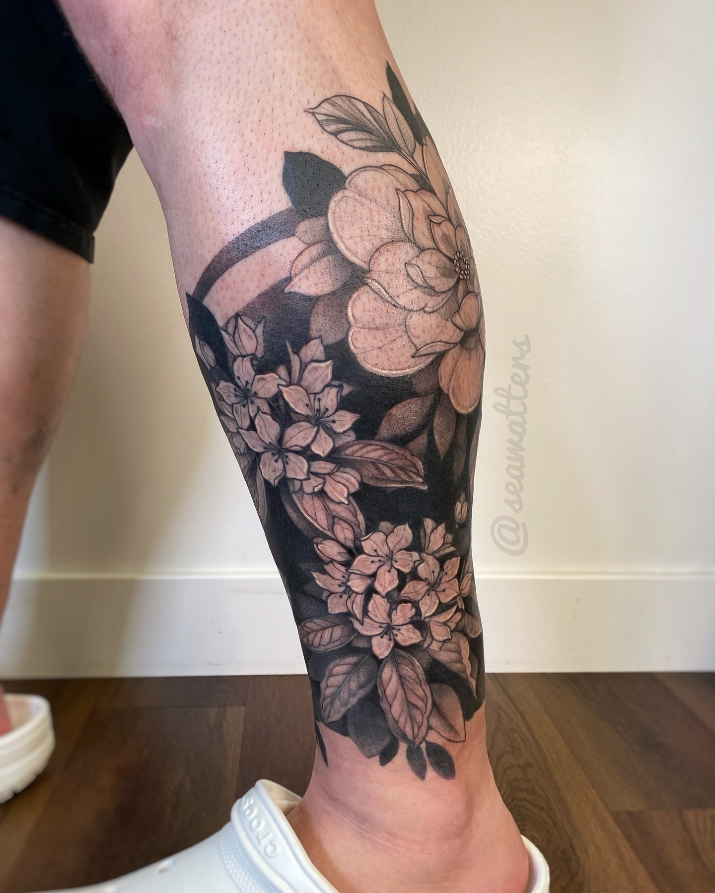 Floral bouquet black and grey tattoo on the calf by Caitlin Watters
