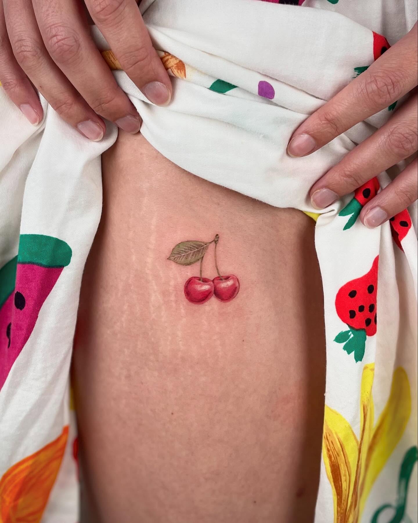 Cherries realism tattoo on the thigh by Jennifer Fuster