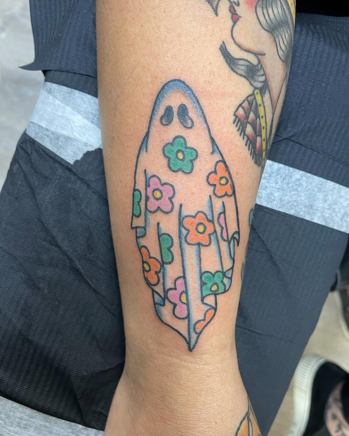 Surfboard with flowers trash polka tattoo on the forearm by Zach Eden