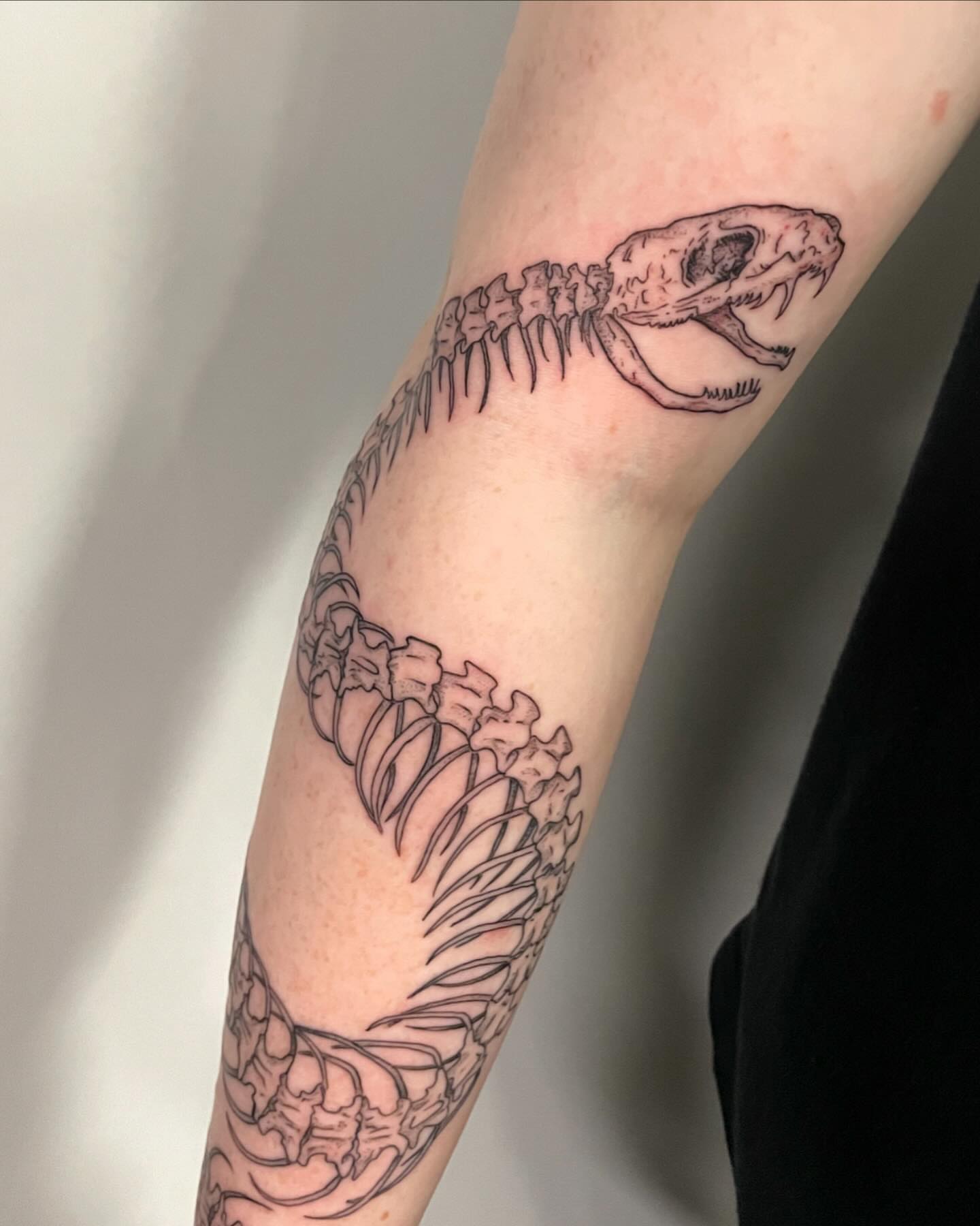 Snake skeleton black and grey tattoo on the forearm by Christen Wolfe CA Tattooer