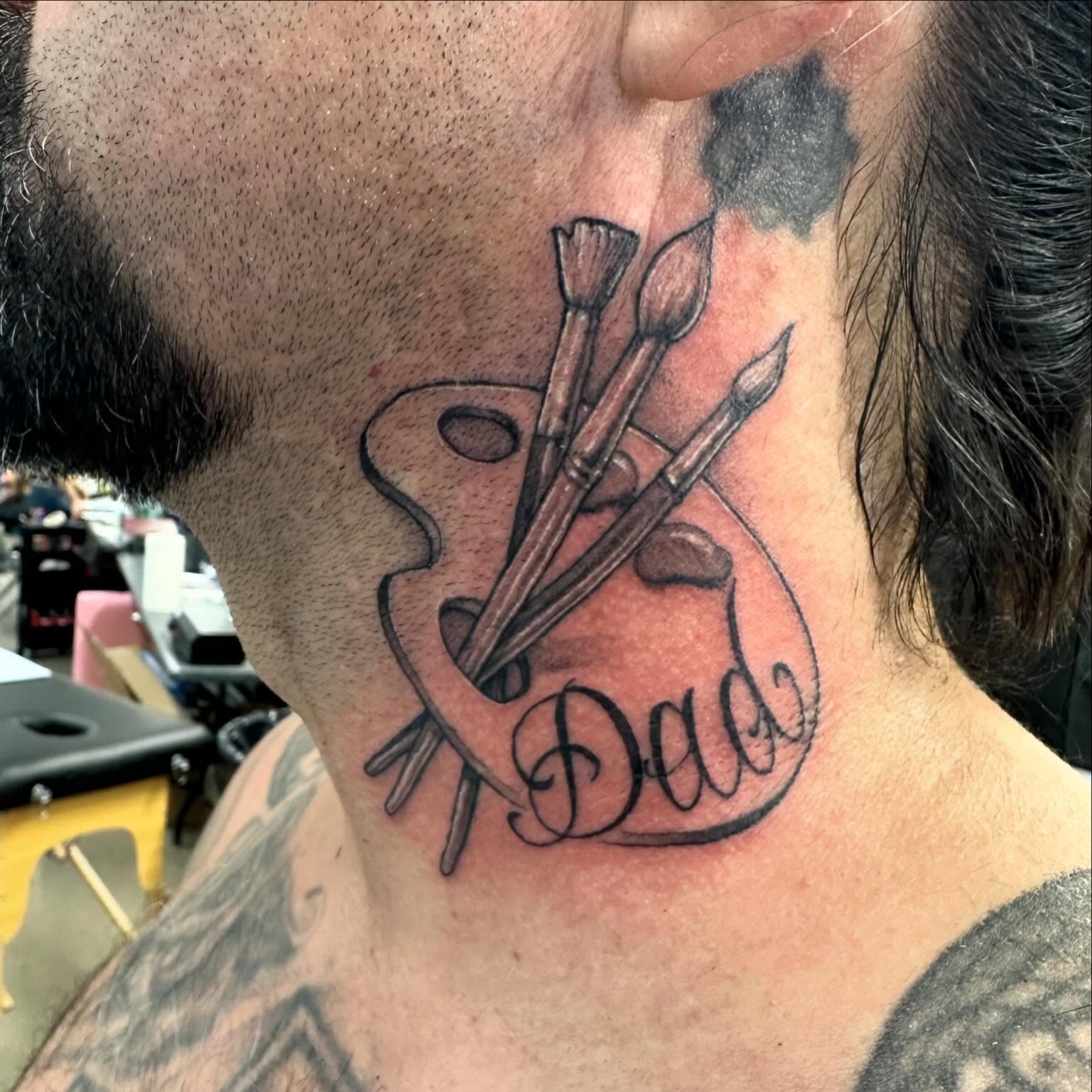 Paintbrushes and palette black and grey tattoo on the neck by Justin Hendrick