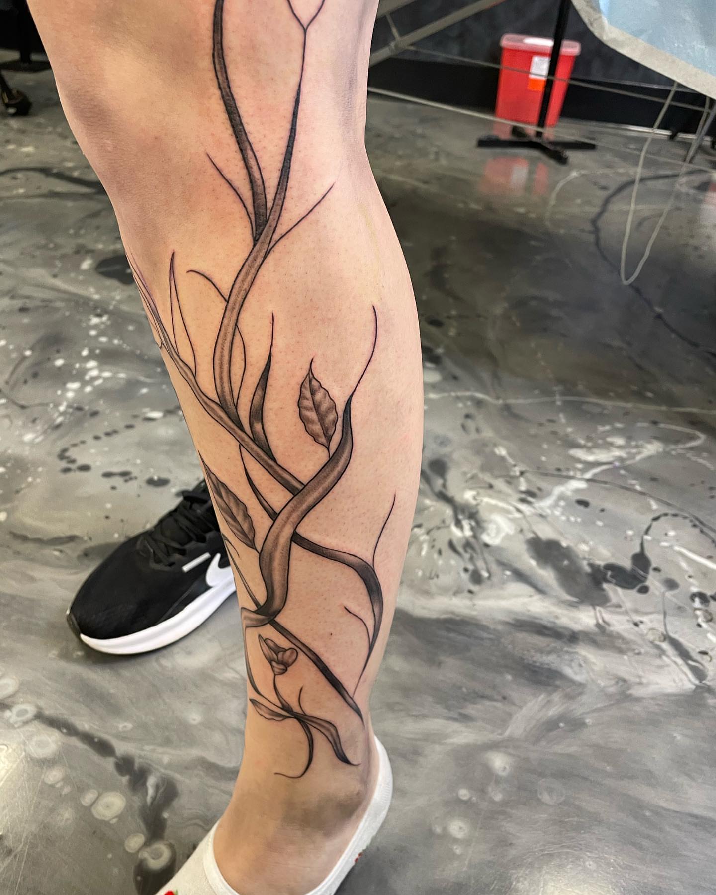 Tree branches black and grey tattoo on the calf by Brandon Anderson