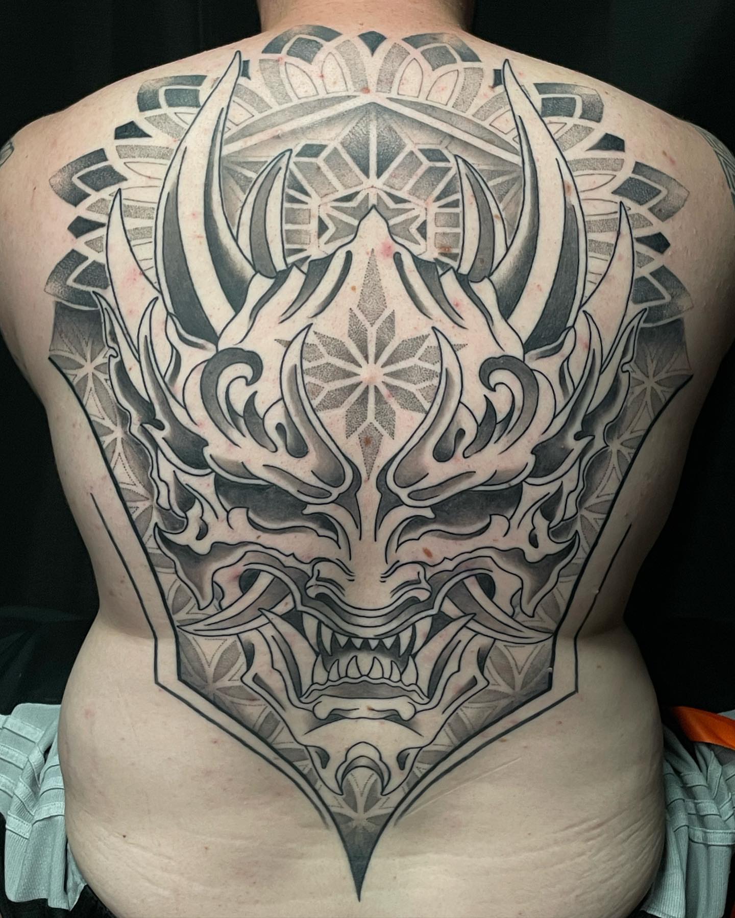 Demon mask geometric tattoo on the back by Jesse (Dreadzilla)
