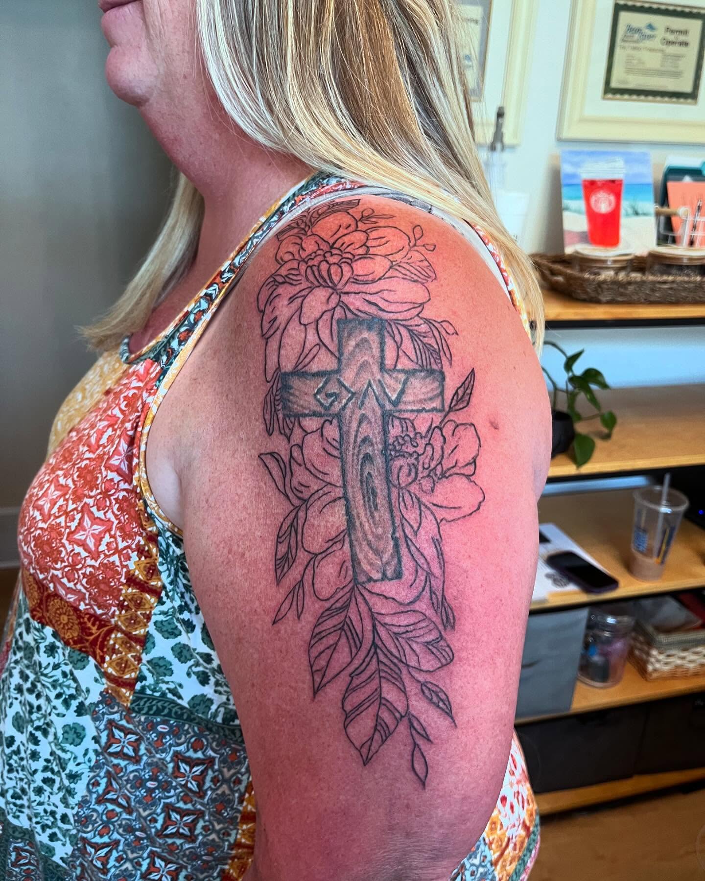 Cross with floral elements black and grey tattoo on the shoulder by Val Maughan