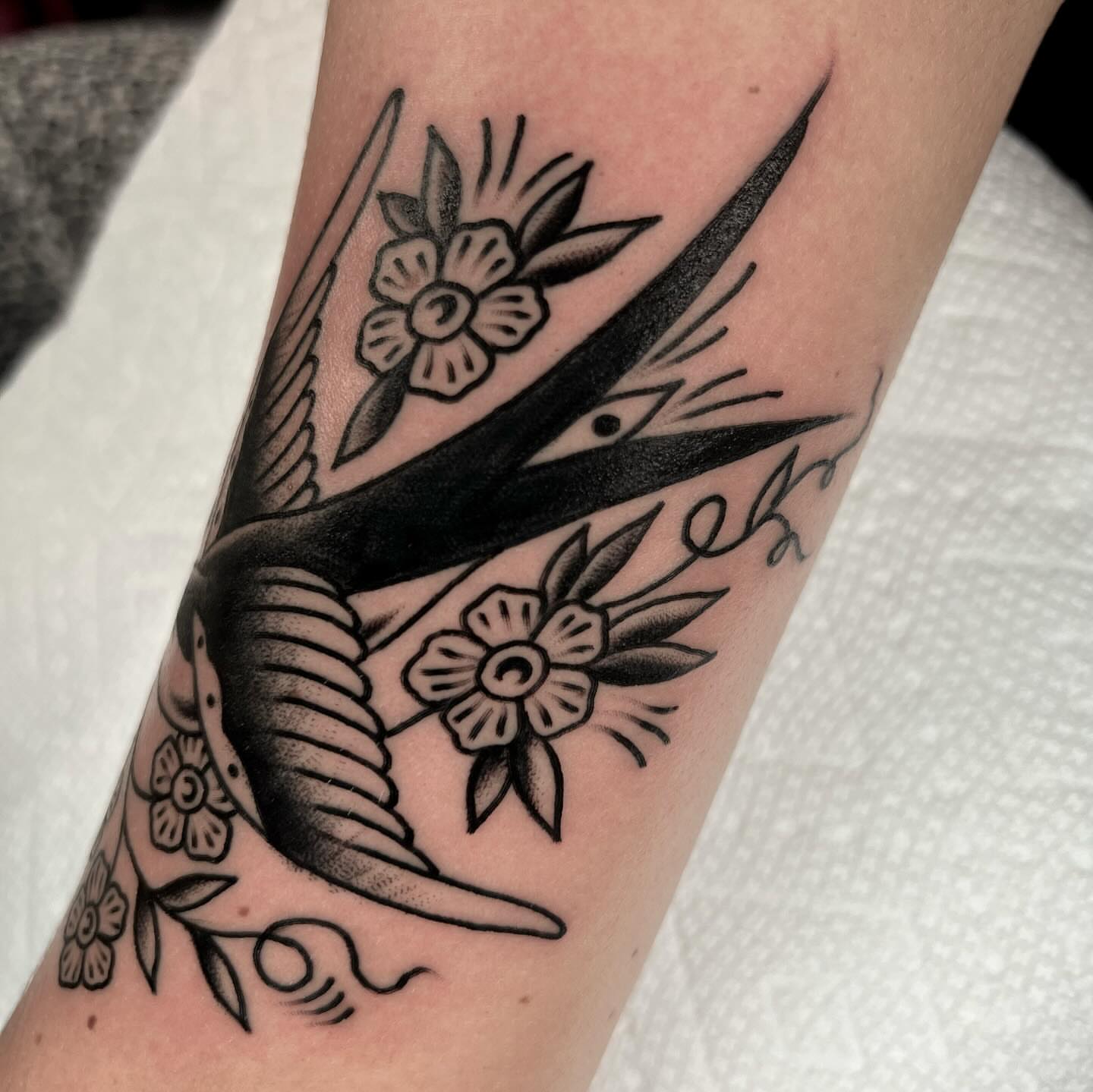 Bird and flowers American traditional tattoo on the forearm by Hailey Johnson