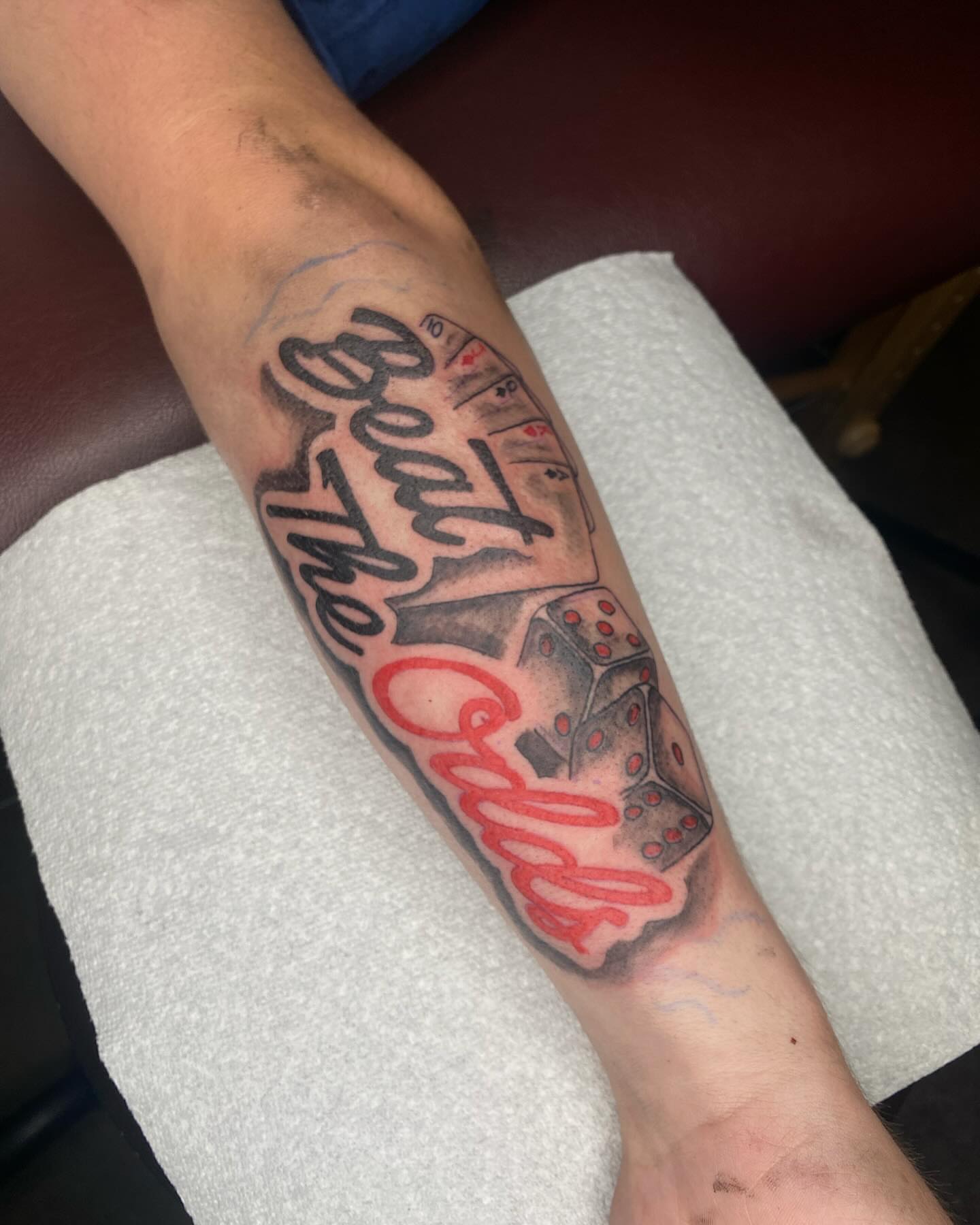 Beat the odds black and grey tattoo on the forearm by Evan Chastain