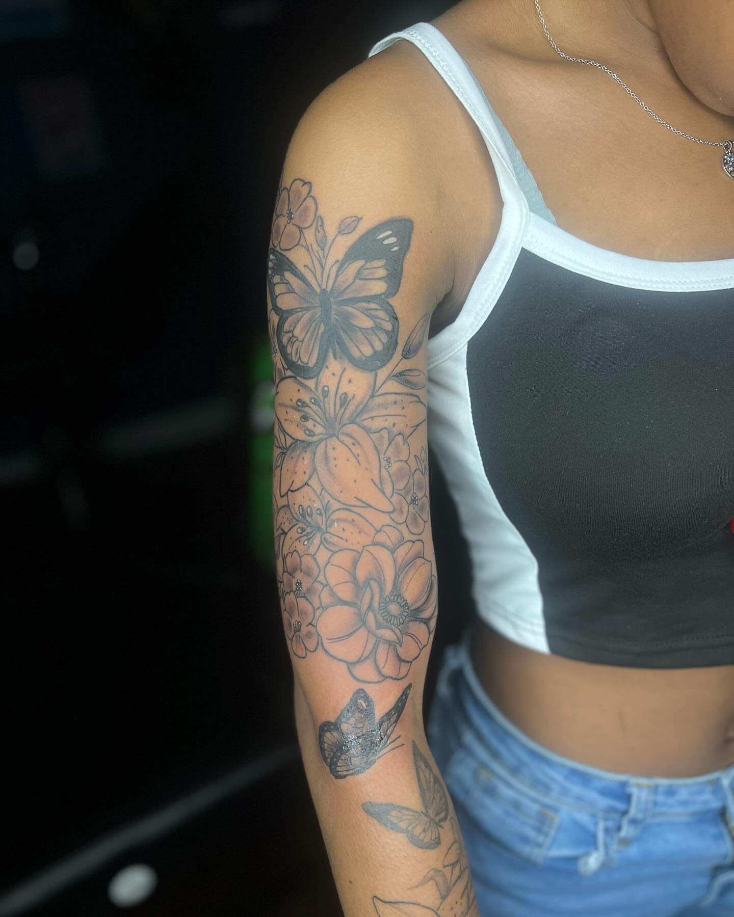 Flowers and butterflies black and grey tattoo on the upper arm by Glass Inkk