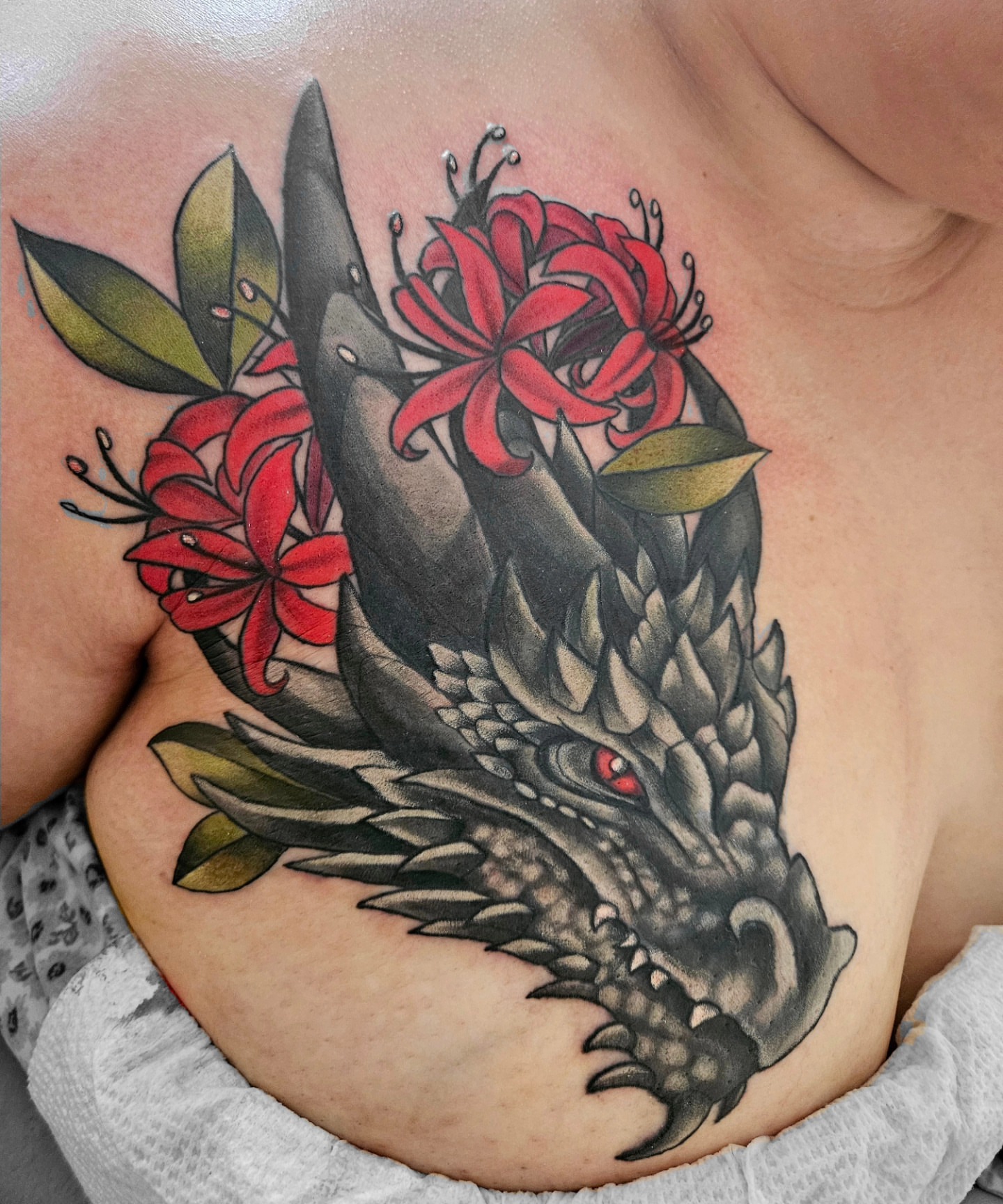 Dragon and flowers American traditional tattoo on the chest by Ginny McCormick, Richmond, Virginia