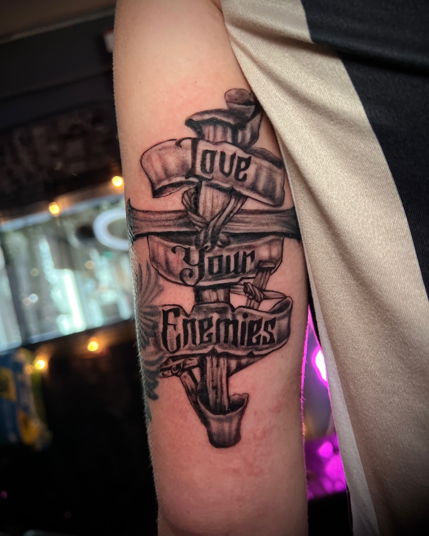 Cross with banners black and grey tattoo on the forearm by Lucky Valenzuela, Lakewood, Colorado