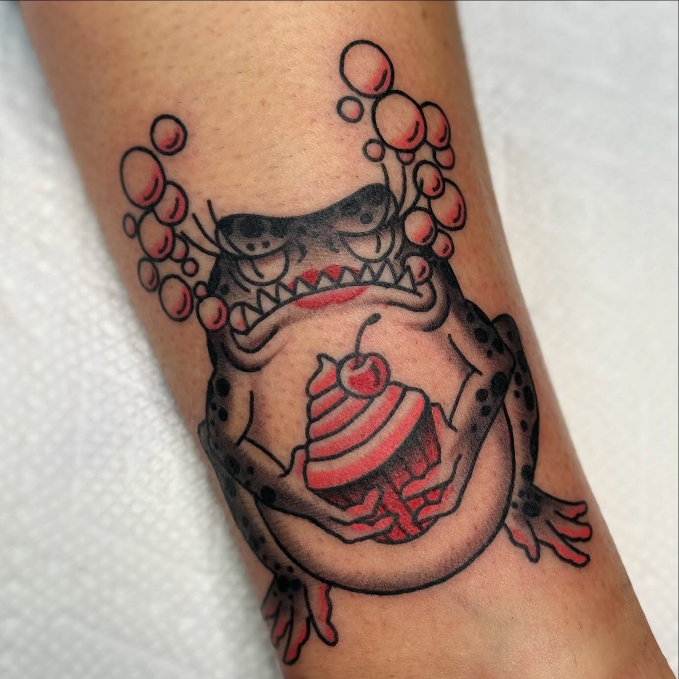 Monster with cupcake American traditional tattoo on the forearm by David Gottschalk