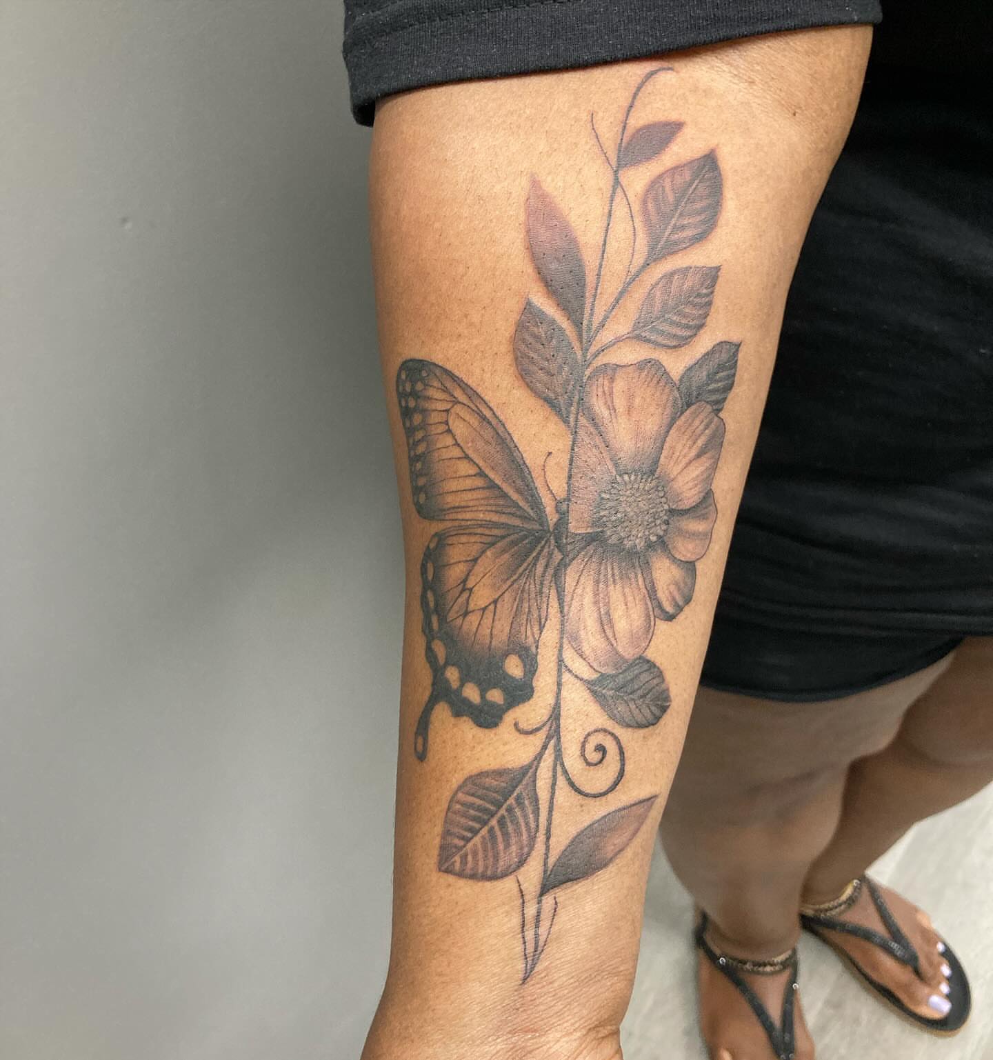 Butterfly and flower realism tattoo on the forearm by Detroit Tattoo Artist