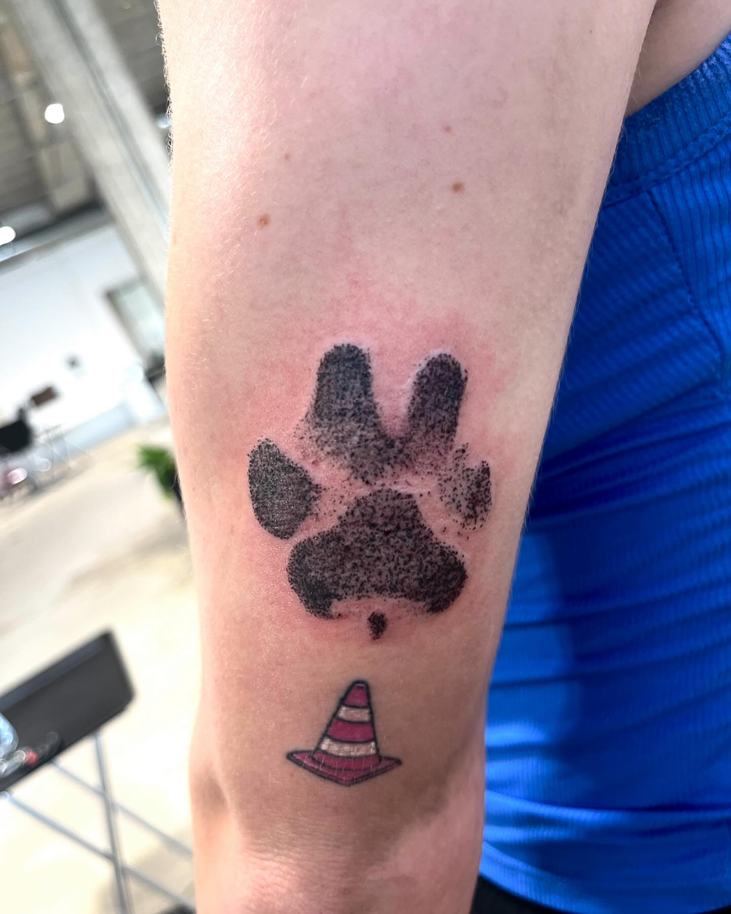 Paw print with traffic cone dotwork tattoo on the forearm by Deville Pinson