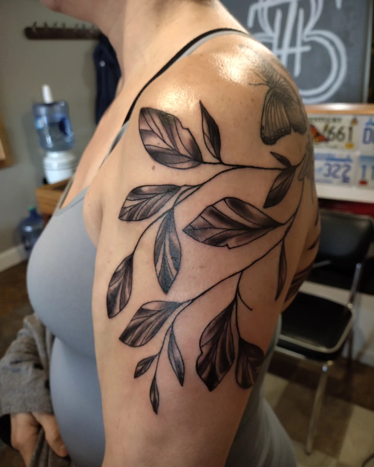 Branch with leaves black and grey tattoo on the shoulder by Matt Williamson