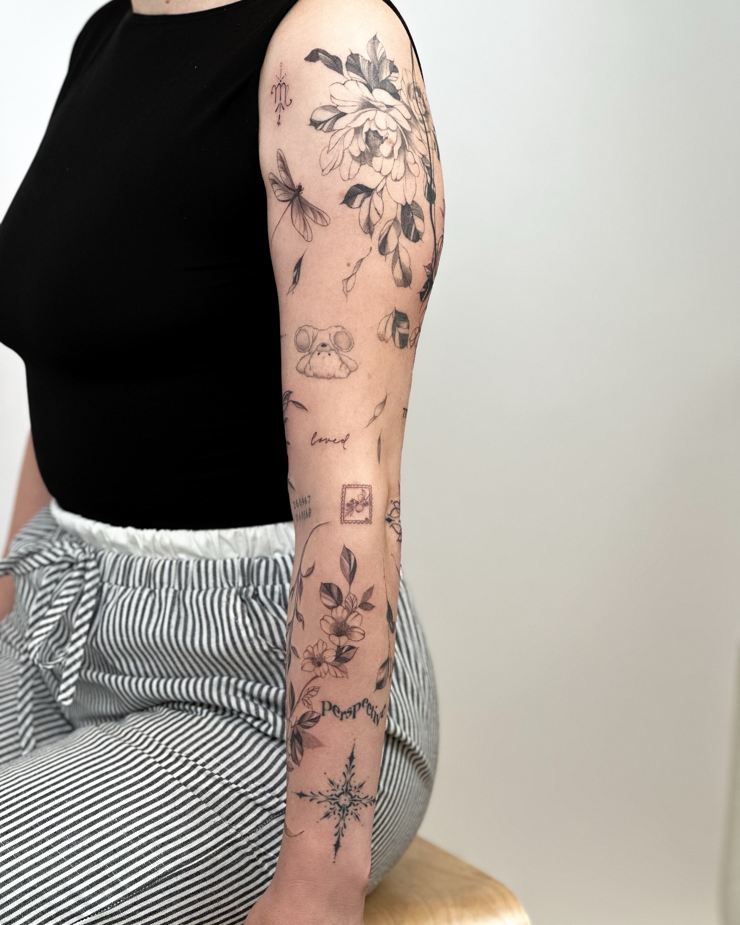Floral and insect motifs black and grey tattoo on the forearm by Liv