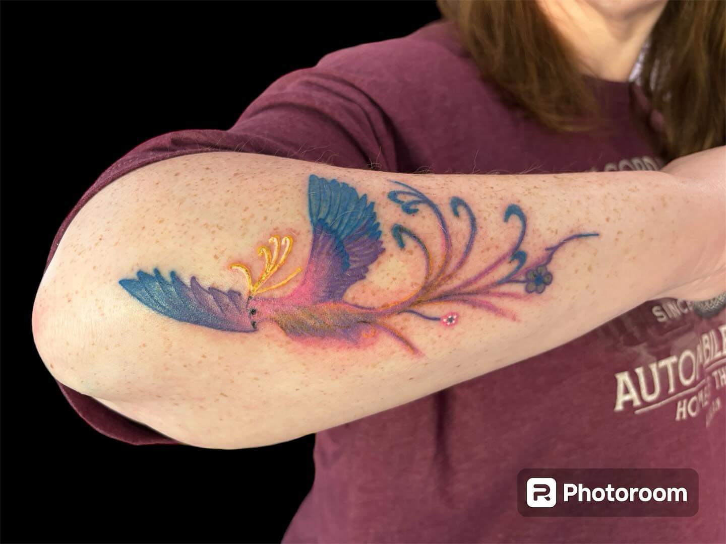 Bird and floral watercolor tattoo on the forearm by Dale Martin