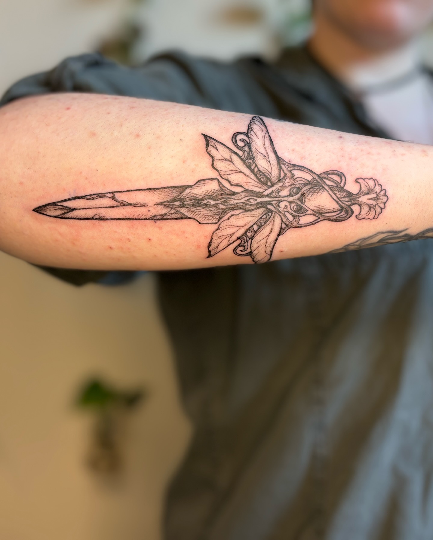Sword and floral black and grey tattoo on the forearm by Wren Cavanaugh Tattoos, Seattle, Washington