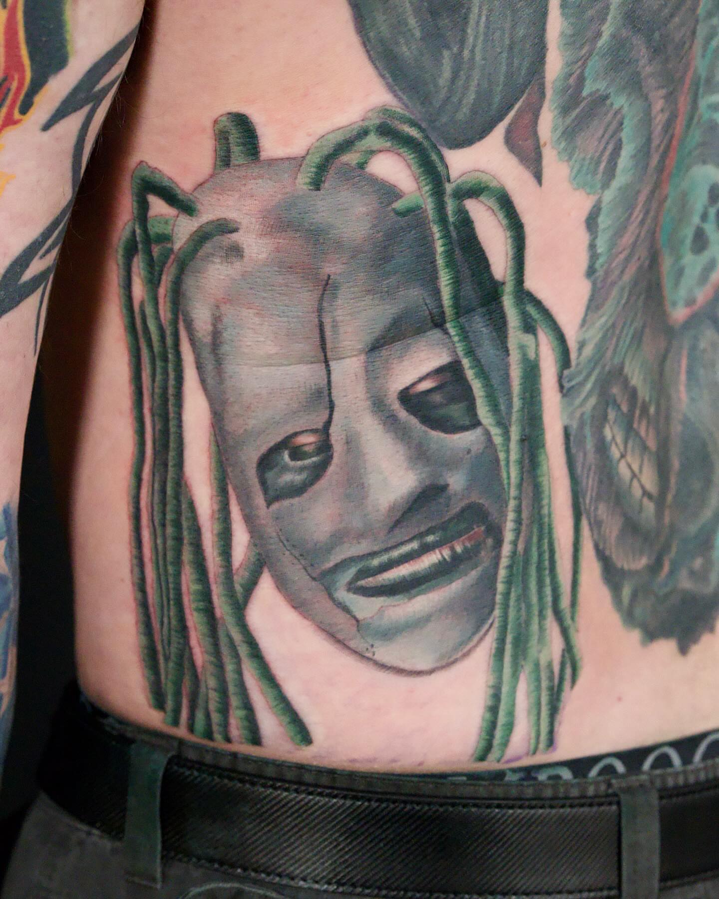 Mask with dreadlocks realism tattoo on the torso by Chris Lochbihler