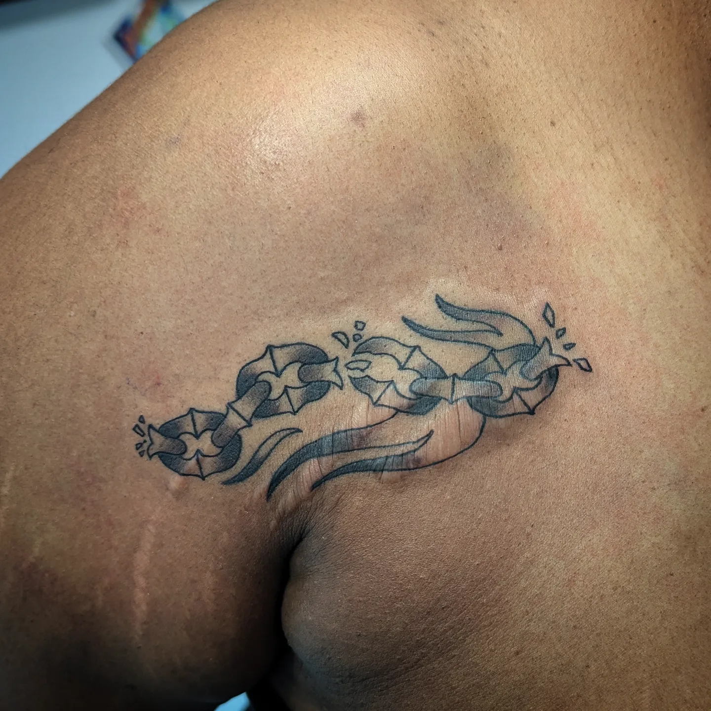Broken chain black and grey tattoo on the shoulder by Lorelei