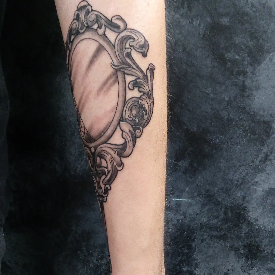 Mirror black and grey tattoo on the forearm by Cassandra Davis