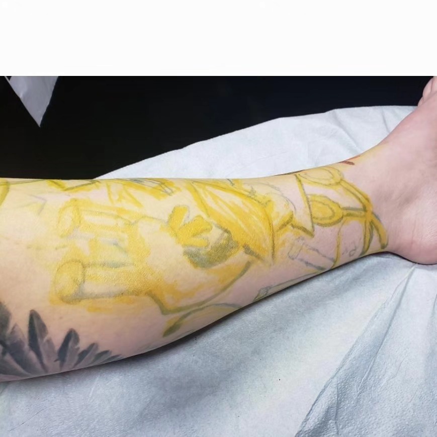 Yellow floral design watercolor tattoo on the forearm by Jake Goss, Salt Lake City, Utah