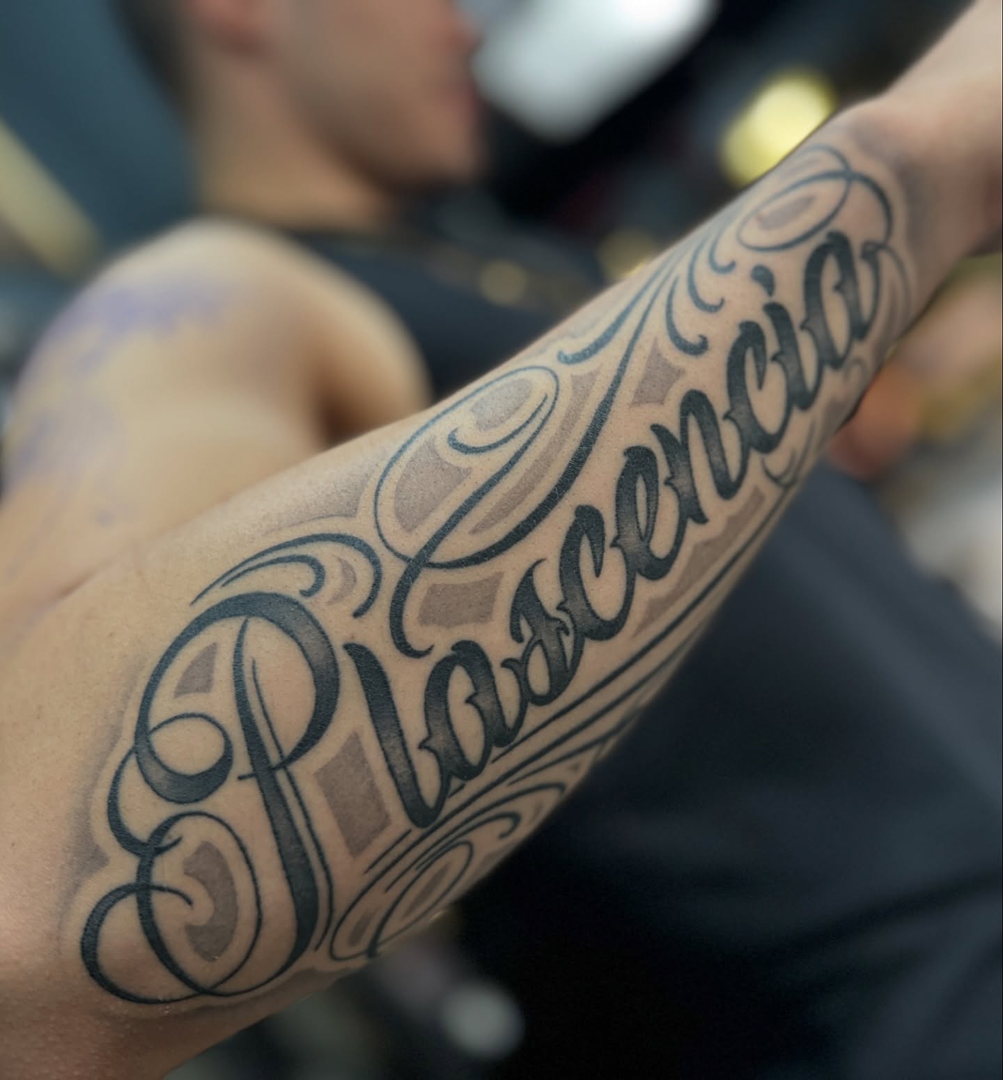Plascencia lettering script tattoo on the forearm by Julio Ferrer