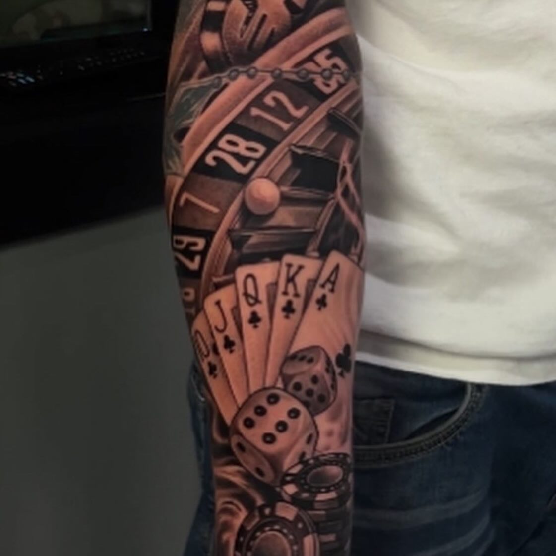Roulette wheel and playing cards realism tattoo on the forearm by Danny Lepore