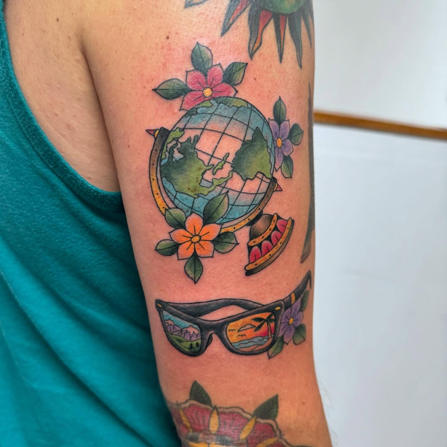 World globe with sunglasses American traditional tattoo on the forearm by McKenna Chalifoux