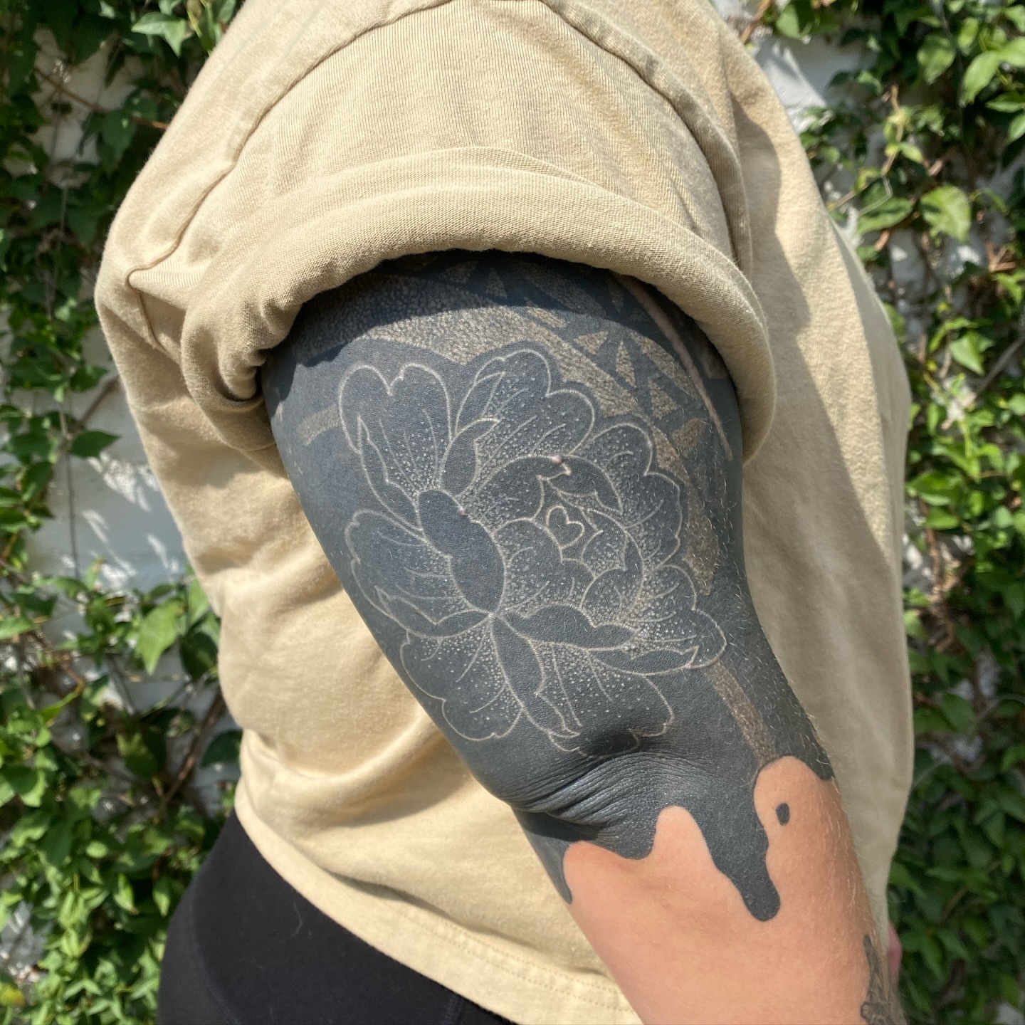 Floral design dotwork tattoo on the upper arm by Emily Miller